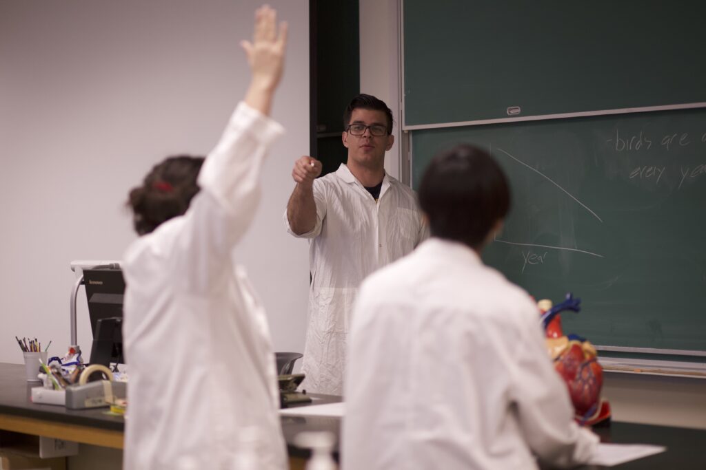 Student raises their arm to answer a question