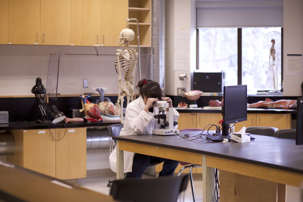 Indigenous student in a biology lab with a microscope.