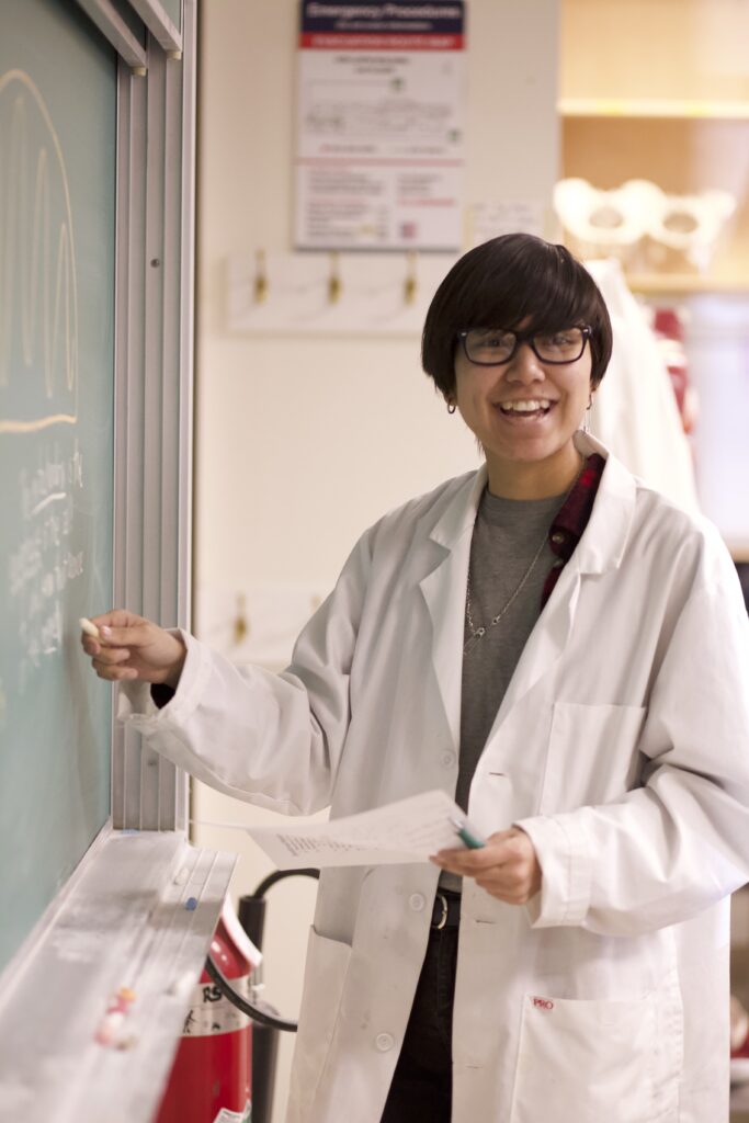 Indigenous student in a biology lab at a chalkboard.