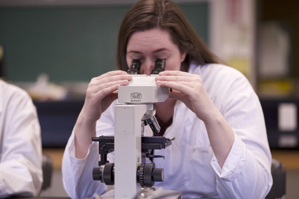 Indigenous student in a biology lab with a microscope.