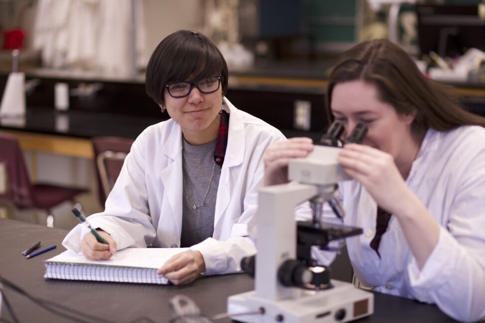 Indigenous students in a biology lab using a microscope..