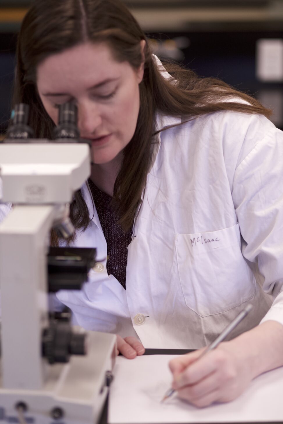 Indigenous student in a biology lab using a microscope.