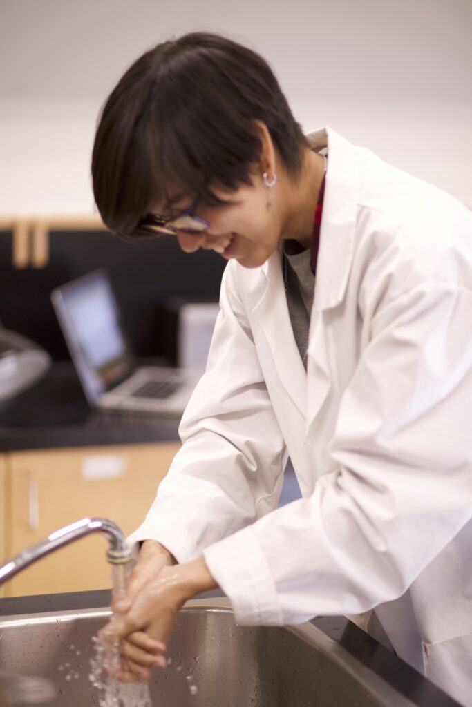 Indigenous student in a biology lab washing hands.